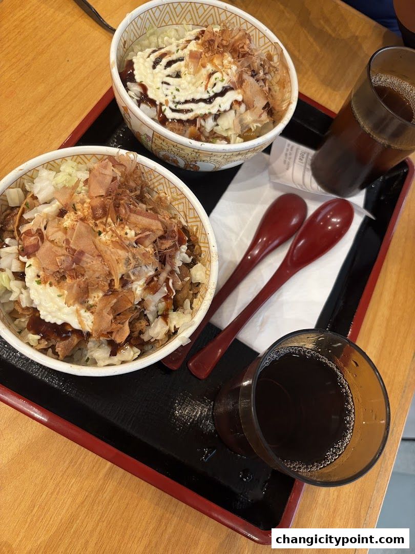 Two bowls of gyudon and two glasses of iced tea on a tray.