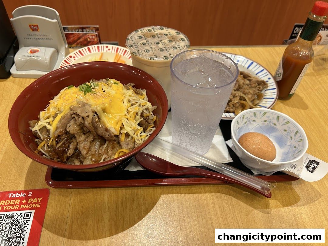 A delicious Sukiya Gyudon meal with cheese, a drink, and a side egg.