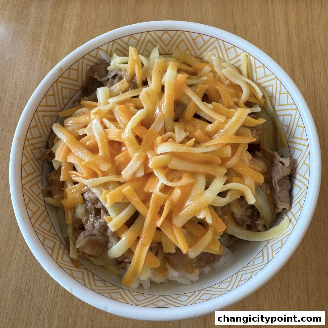 A bowl of gyudon topped with shredded cheese and sauce.