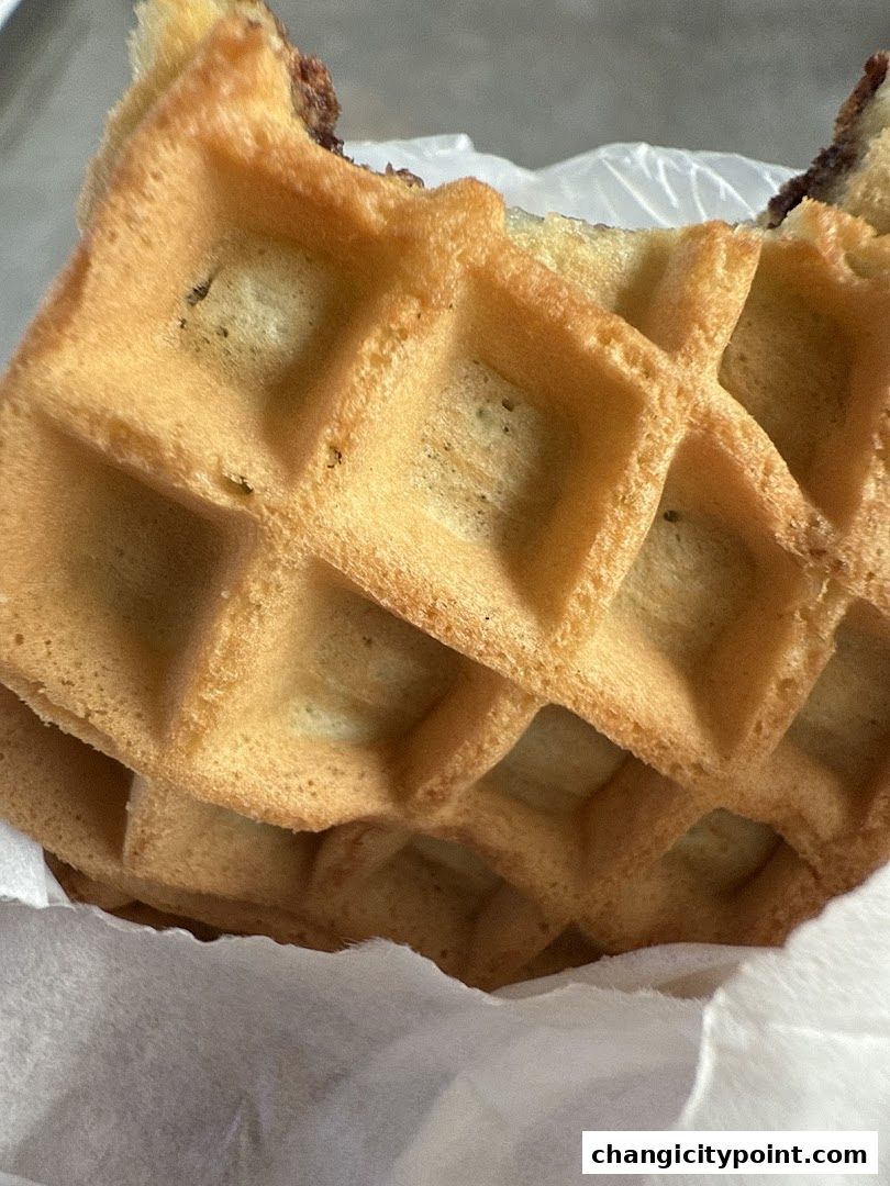 A close-up shot of a delicious waffle with a bite taken out, revealing a chocolate filling.