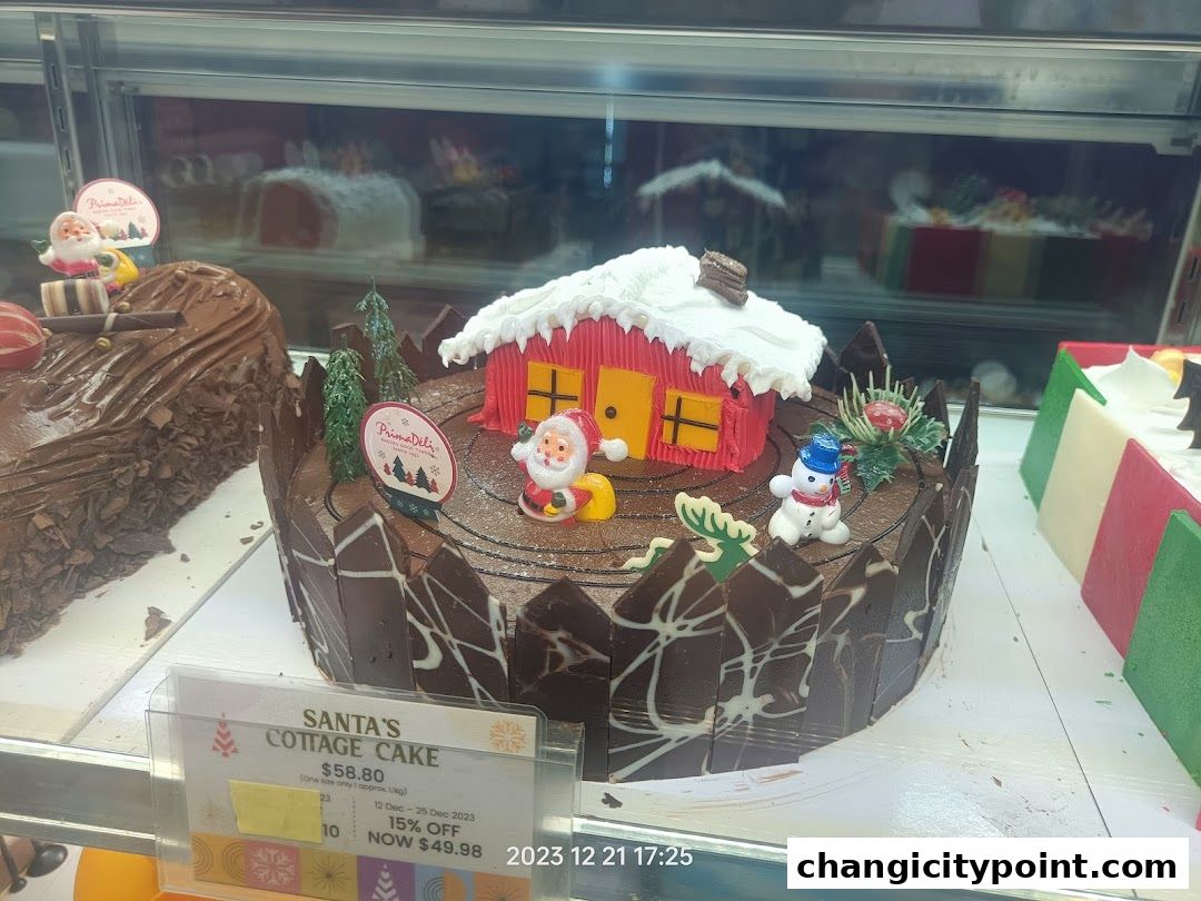 A festive chocolate cake decorated with Santa, a snowman, and a cottage, displayed in a bakery case.