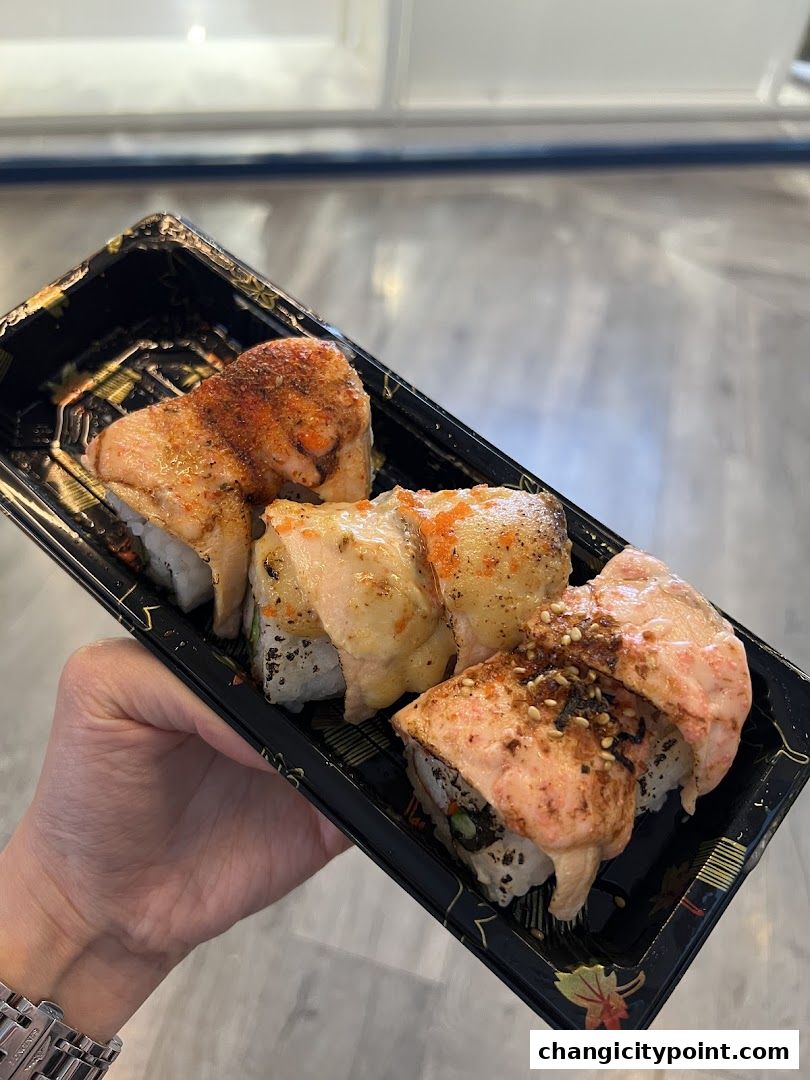A hand holds a black container filled with delicious-looking salmon sushi rolls.