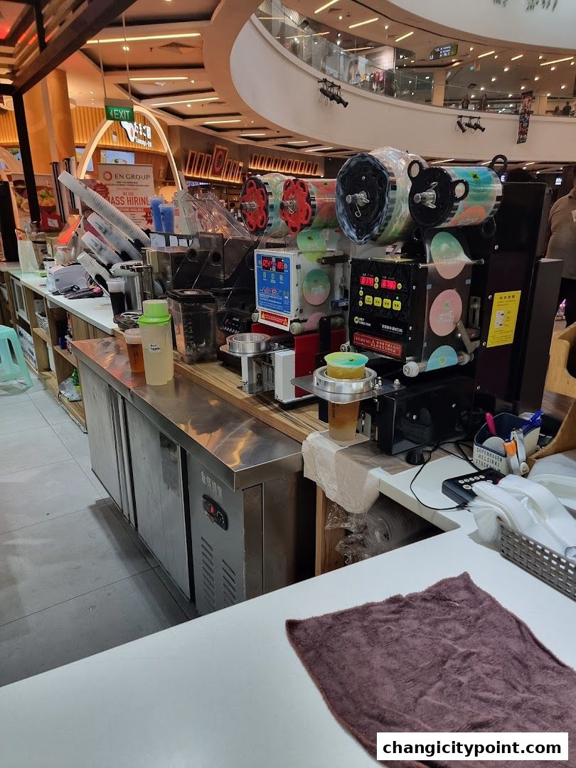A beverage counter with sealing machines and cups, likely for a bubble tea shop.