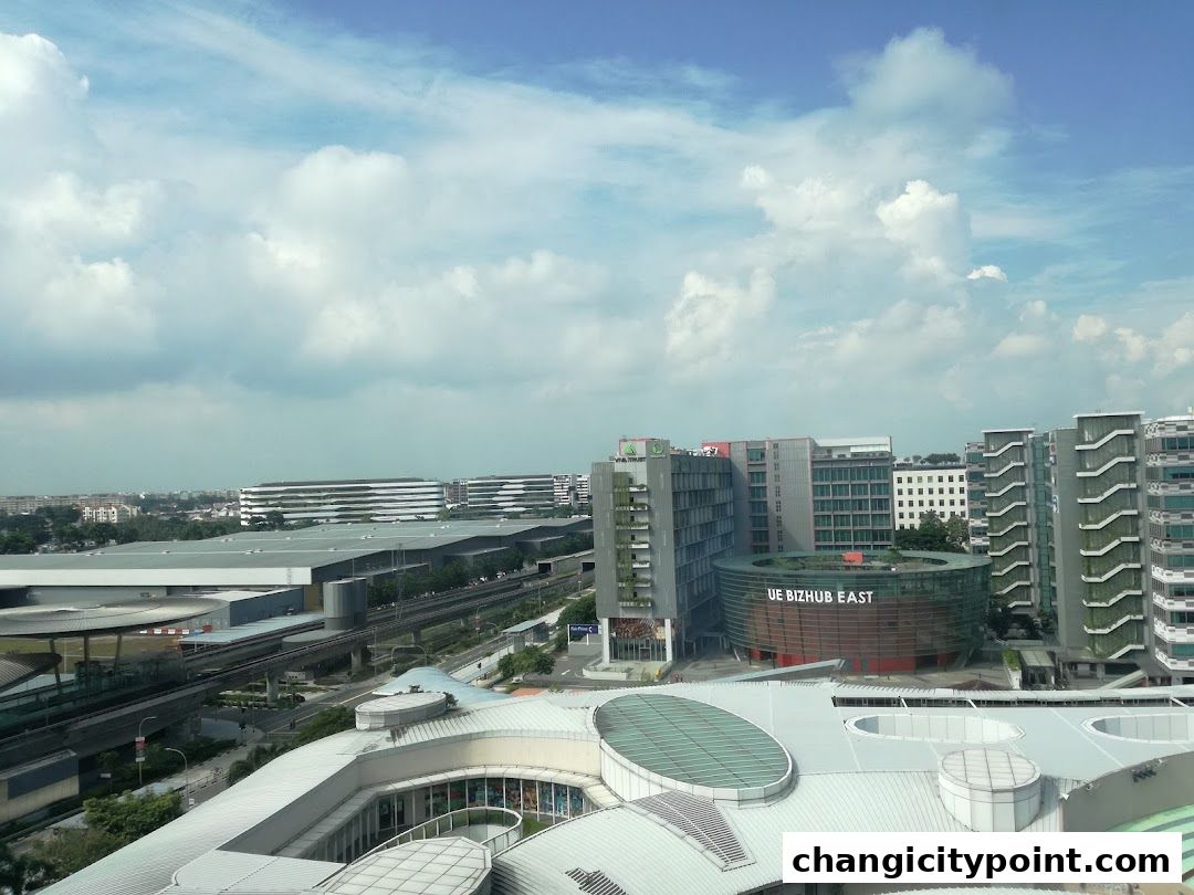 Aerial view of UE BizHub East building and surrounding cityscape under a cloudy sky.