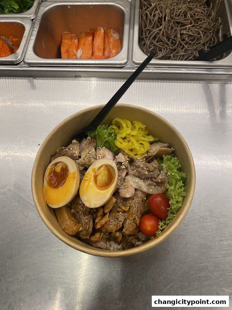 A bowl of rice topped with meat, egg, lettuce, and tomatoes, with ingredients in the background.
