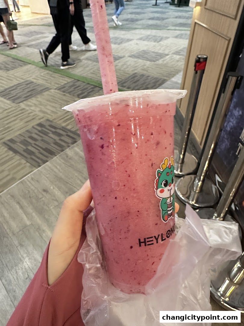 A hand holds a refreshing pink beverage with a straw from Hey Long Cha.