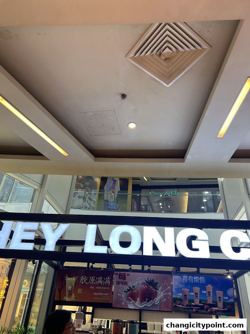 The illuminated sign for 'HEY LONG C' tea shop with promotional images of drinks and fruits.