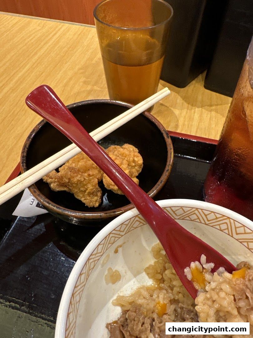 A close-up of a Sukiya Gyudon meal with fried chicken and drinks.