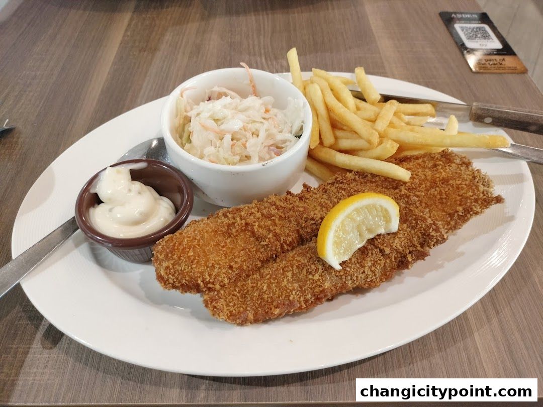 A plate of crispy fish and chips with coleslaw and tartar sauce.