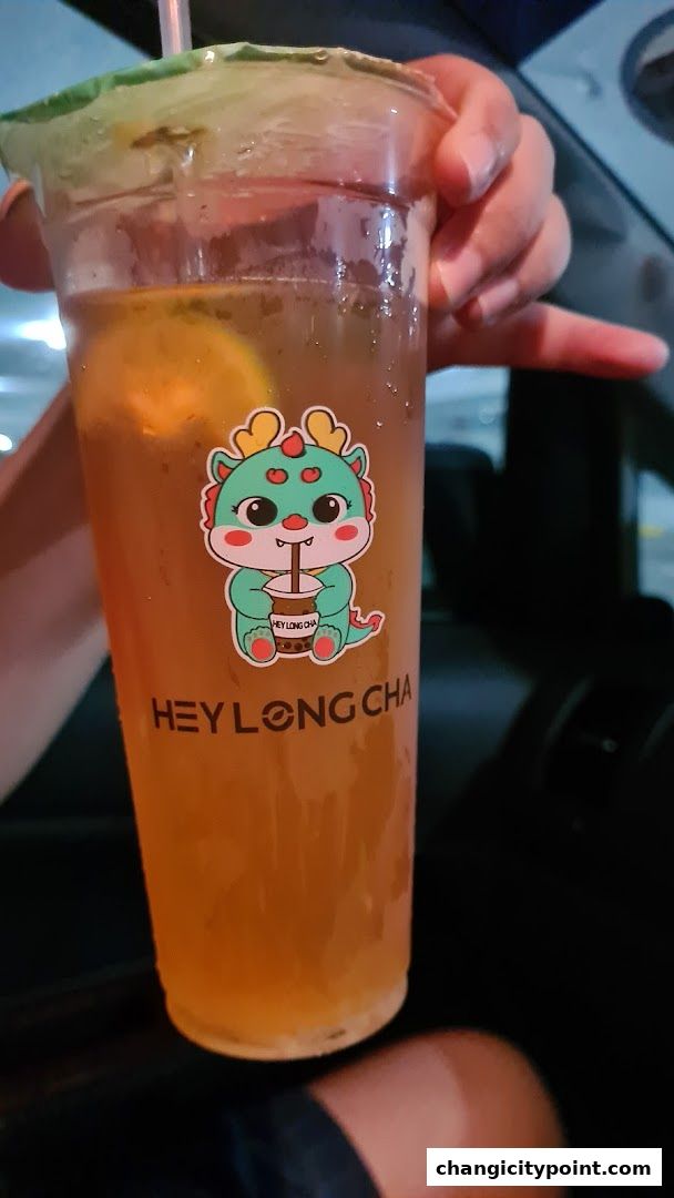 A person holds a refreshing bubble tea from Hey Long Cha with a cute dragon sticker.