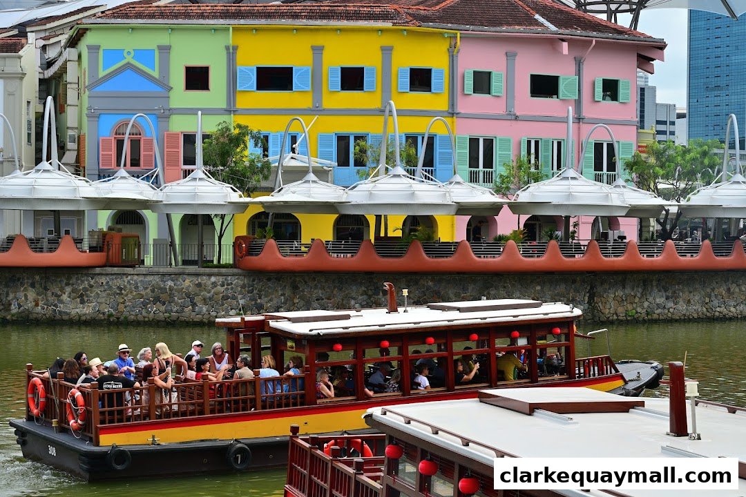 A Singapore River Cruise boat with passengers passes colorful buildings along the waterfront.