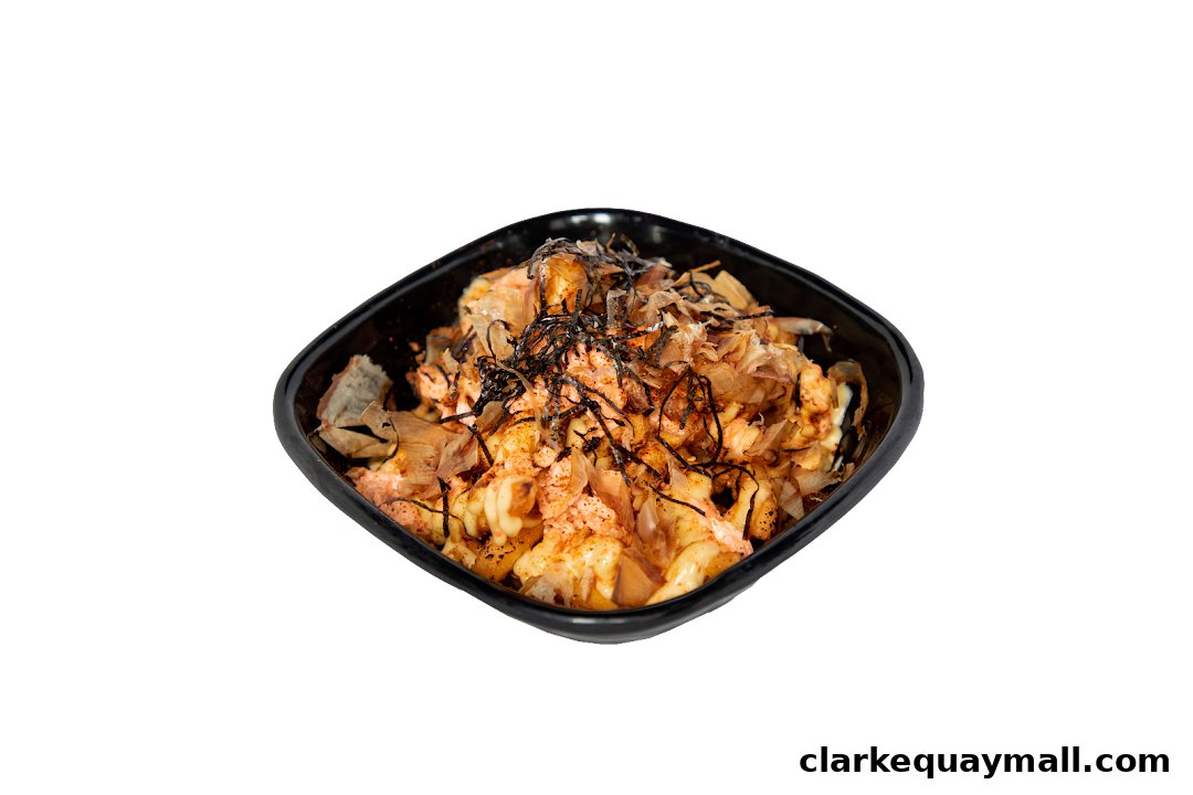 A close-up of a black bowl filled with a creamy, savory dish topped with bonito flakes and seaweed.