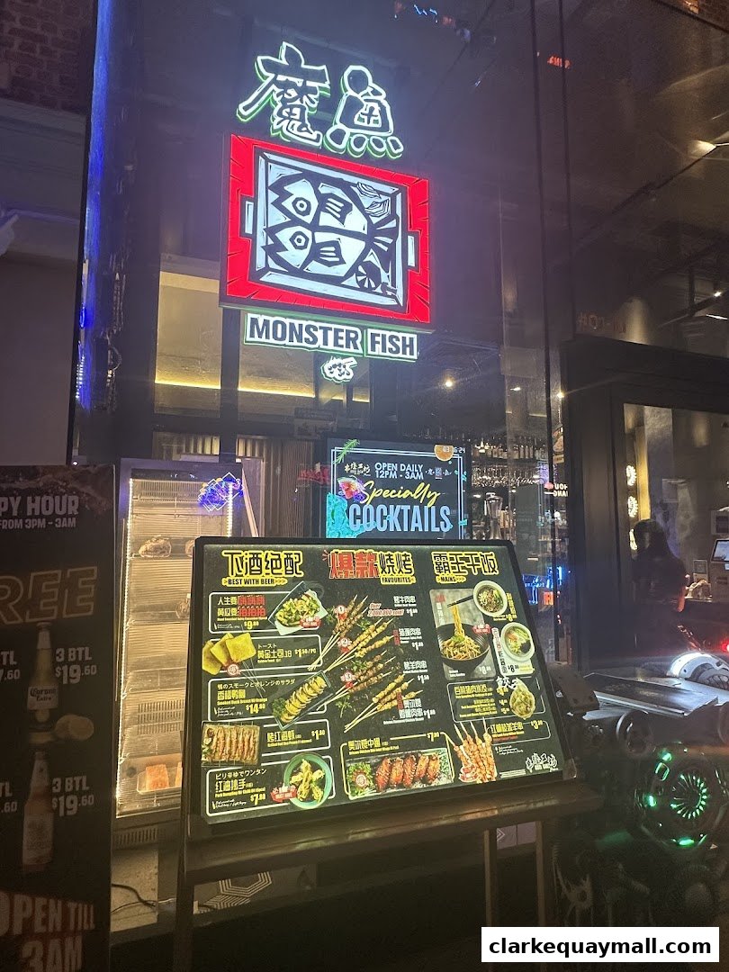A brightly lit shop front with a neon sign for 'Monster Fish' and a menu display.