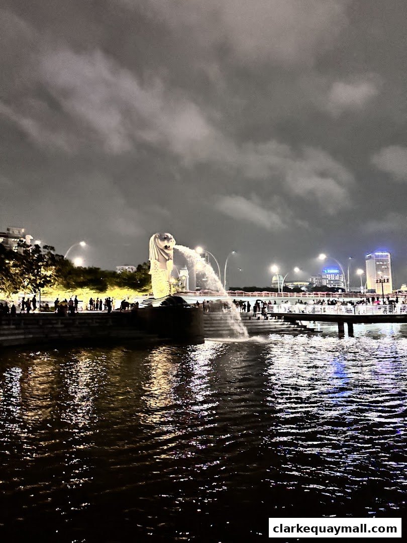 Night view of the Merlion statue at Marina Bay with people and city lights.