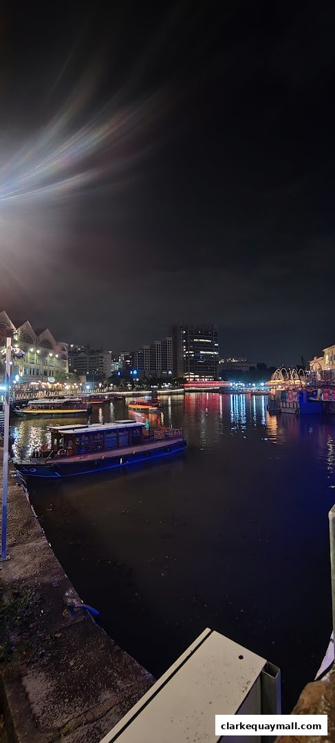 Night view of a river with boats and illuminated buildings in Clarke Quay.