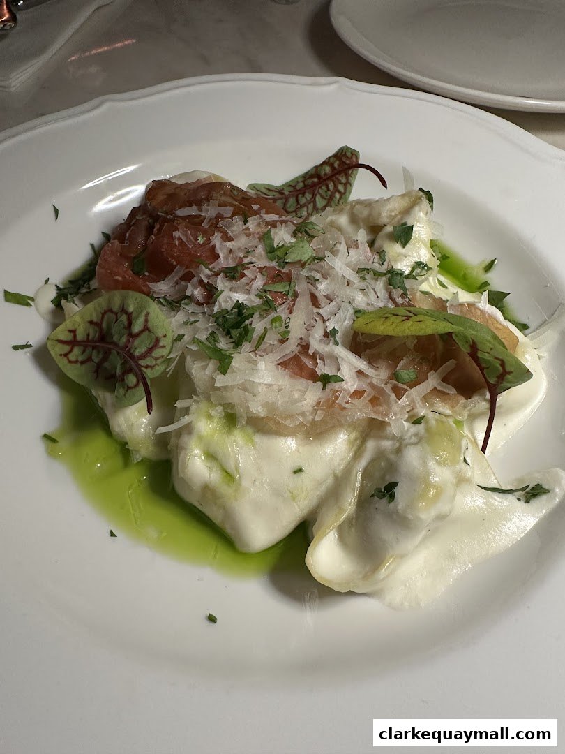 A plate of ravioli with prosciutto, cheese, and a green sauce.
