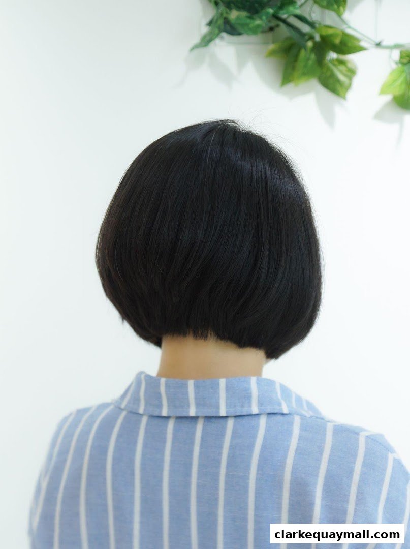 Back view of a person with a sleek, dark bob haircut and a blue and white striped shirt.