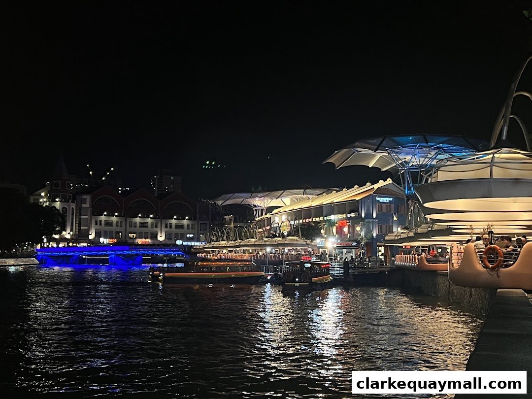A nighttime view of a riverfront with boats and illuminated buildings.