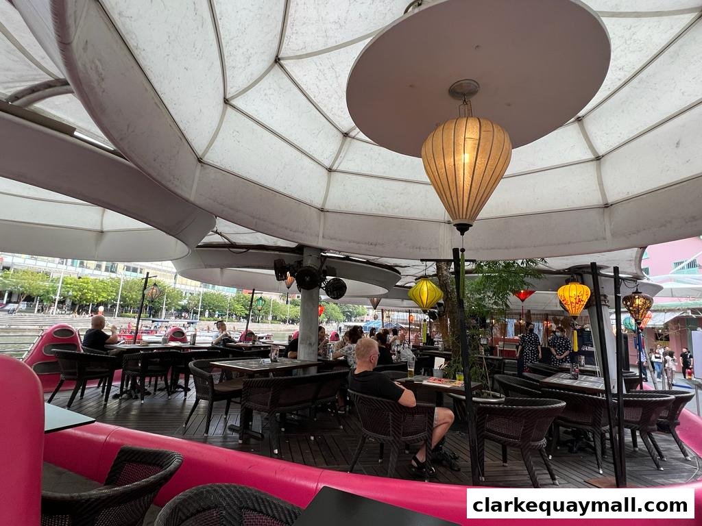 People dining at tables under a large white canopy with decorative lanterns.
