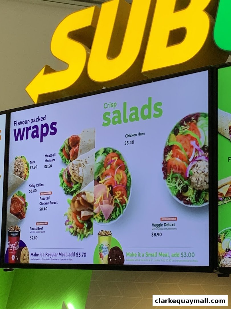A digital menu board displaying wraps and salads with prices at Subway.