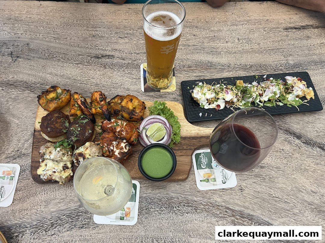 A wooden table with a platter of grilled meats, appetizers, and drinks.