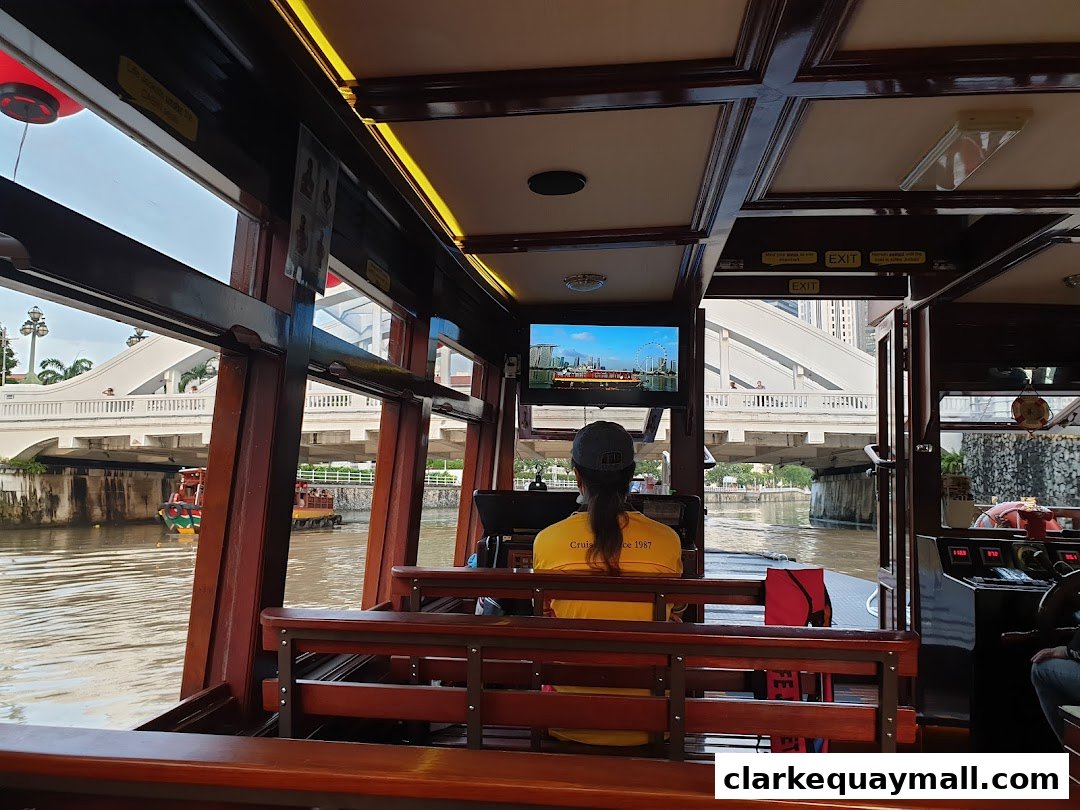 View from inside a Singapore River Cruise boat, looking out at a bridge and the water.