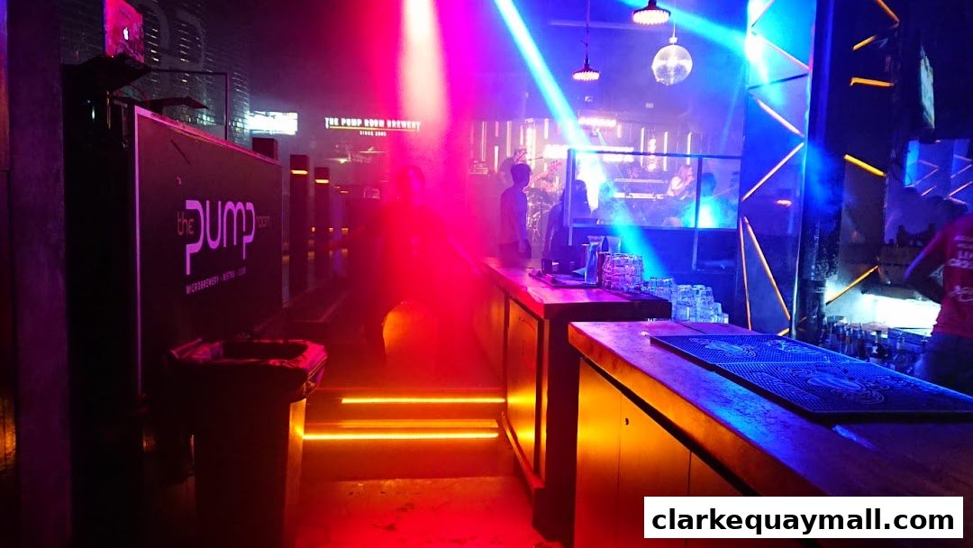 Interior of a bar with colorful lights, a DJ booth, and a bar counter.