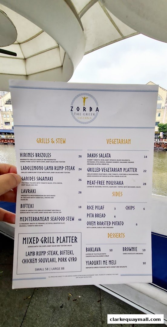 A menu from Zorba The Greek Taverna featuring grills, stews, vegetarian options, sides, and desserts.
