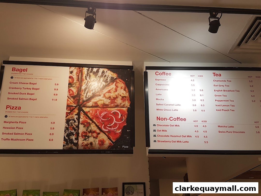 A menu board displaying bagels, pizzas, coffee, tea, and non-coffee drinks with prices.