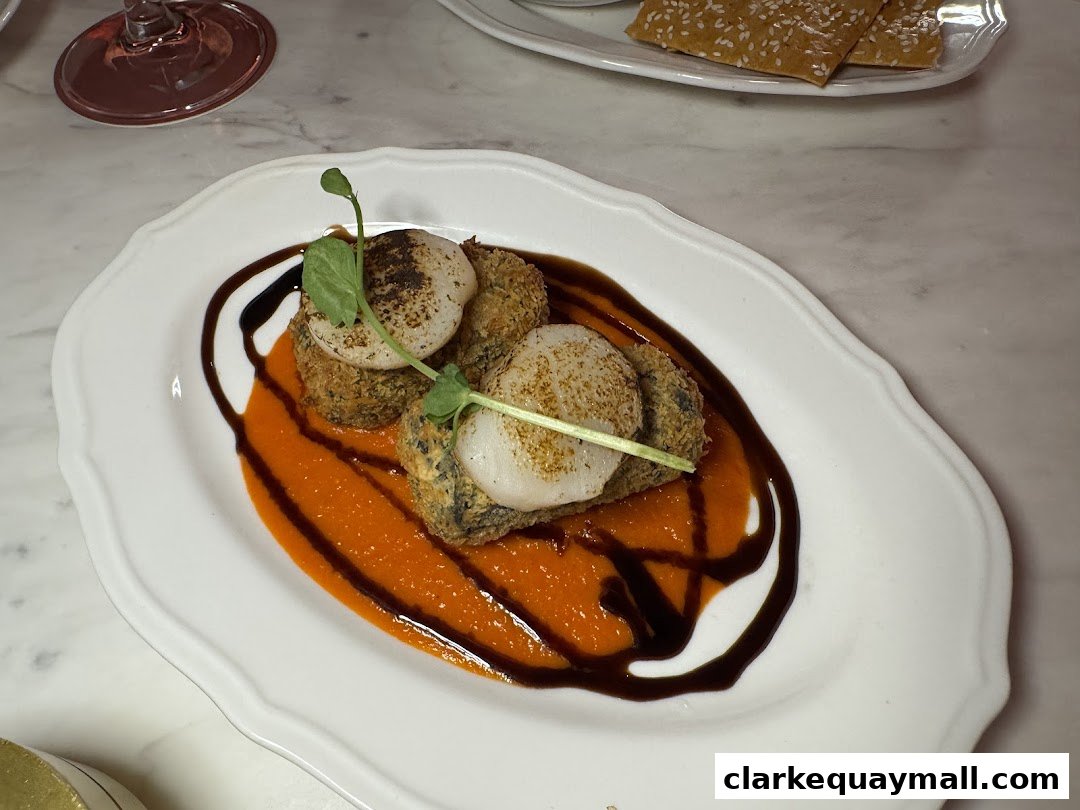 A beautifully plated dish featuring scallops on a bed of sauce with a garnish.