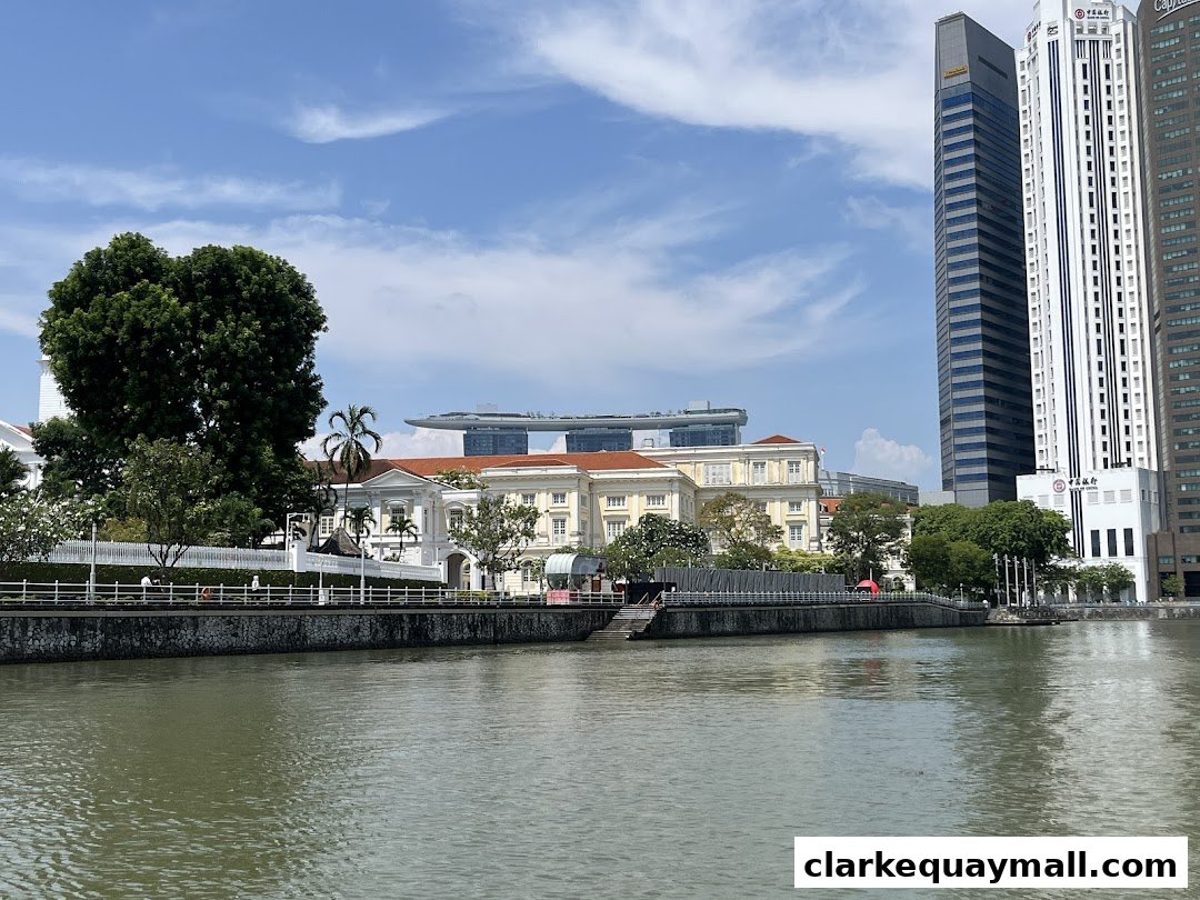 A scenic view of the Singapore River with historic buildings and modern skyscrapers under a blue sky.