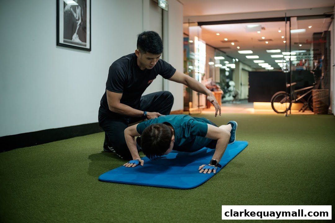 A personal trainer guides a client through a push-up exercise on a blue mat.