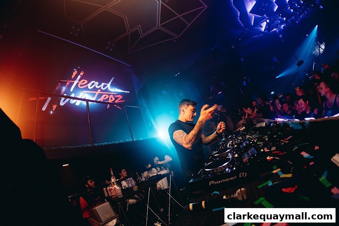A DJ performs for a crowd at Zouk Singapore, with a 'Headhunterz' logo displayed.