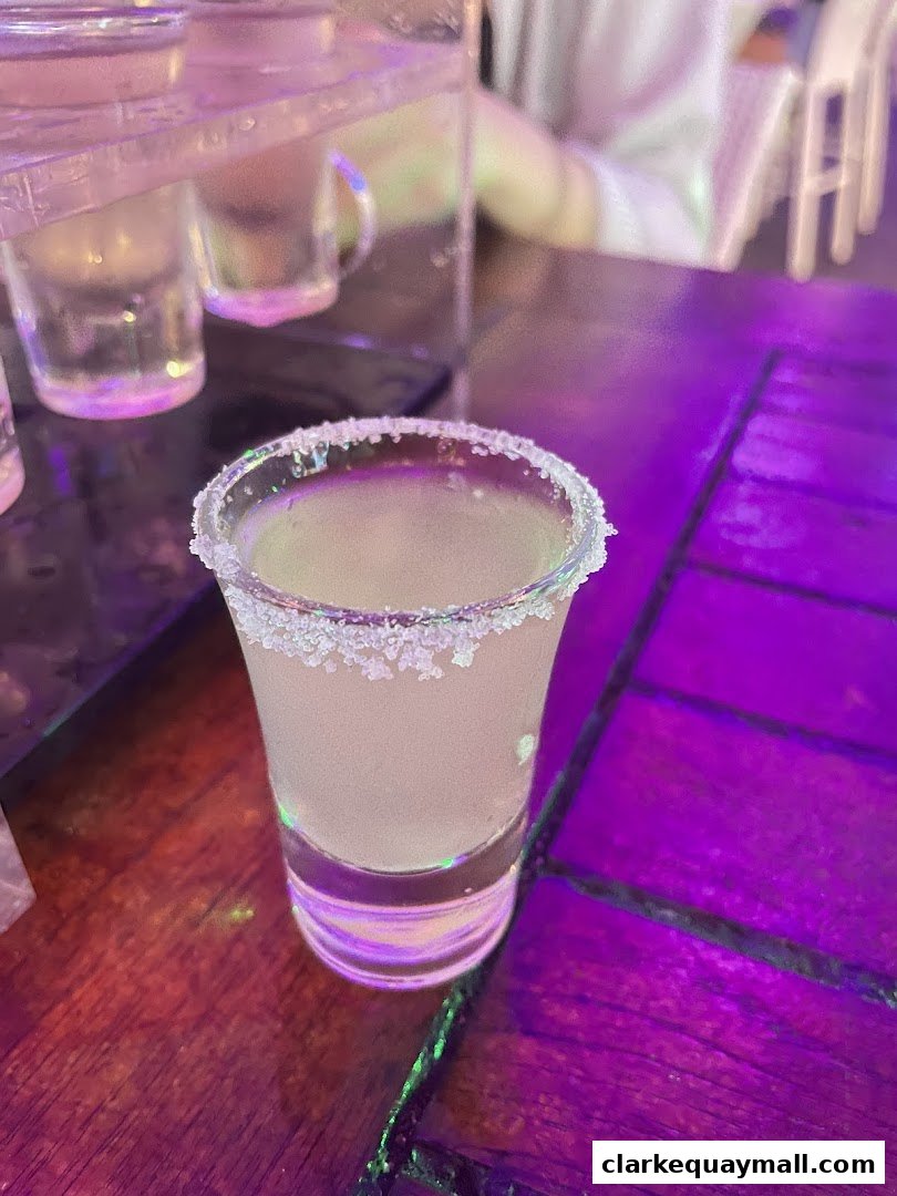 A close-up shot of a shot glass with a salt rim on a wooden table.
