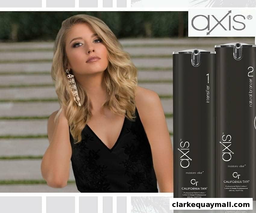 A blonde woman poses next to two bottles of tanning lotion with the brand logo.