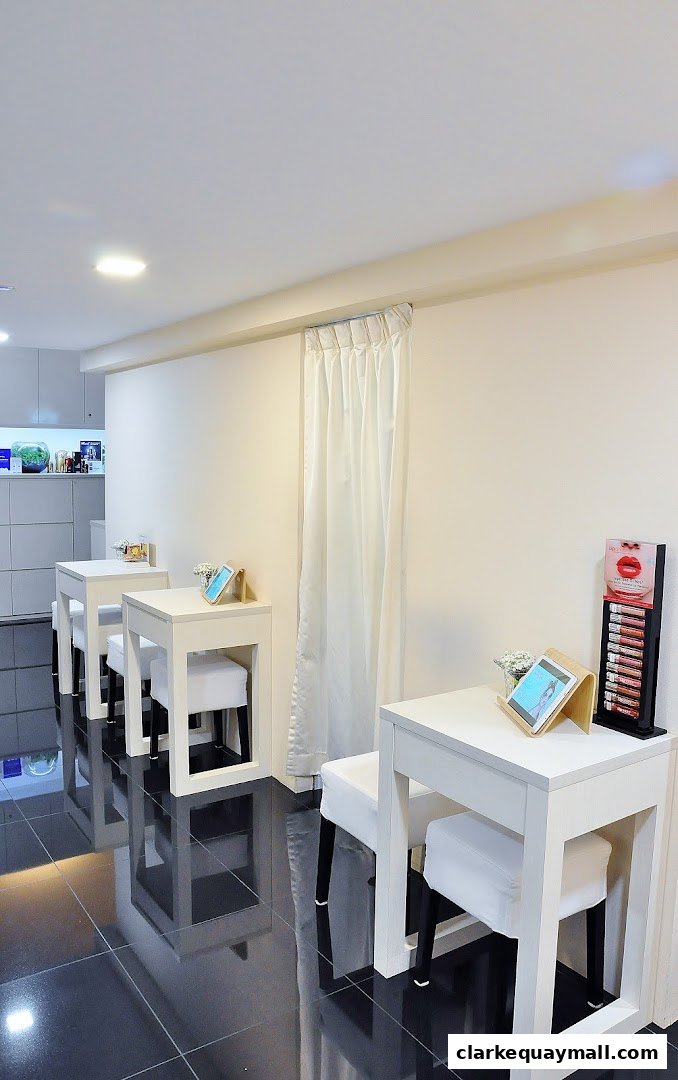 Interior of a clean, modern beauty salon with white tables and chairs, and product displays.