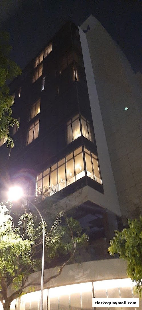 A modern building with illuminated windows and trees at night.