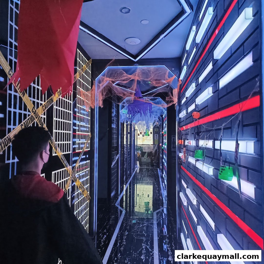 A person walks down a Halloween-themed corridor with caution tape and spooky decorations.