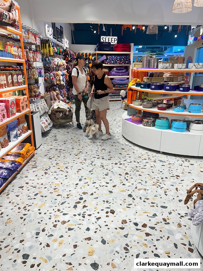 Two women with dogs browse a well-stocked pet supply store with colorful merchandise.