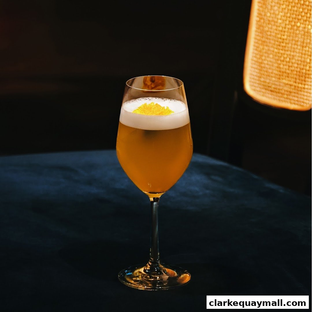 A close-up shot of a golden cocktail with foam and a yellow garnish in a wine glass.