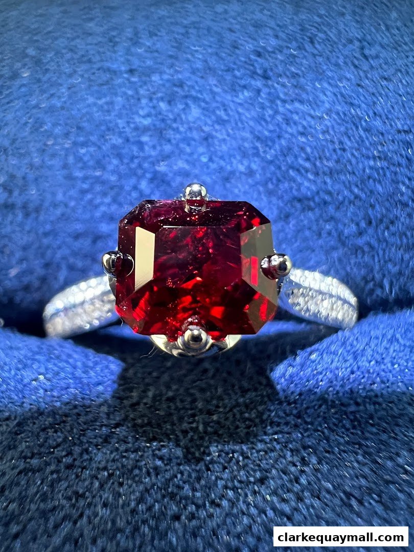 A close-up shot of an exquisite ruby and diamond ring on a blue velvet surface.