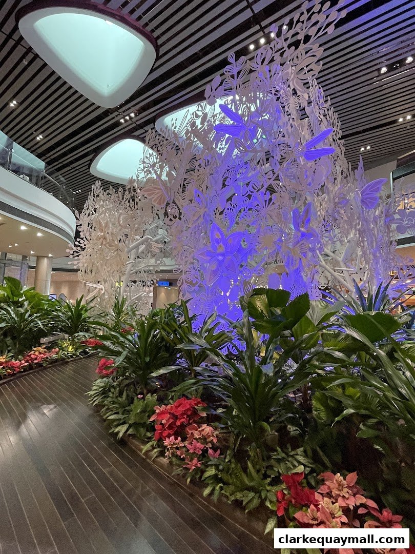 A beautifully decorated walkway with lush plants and a large, illuminated floral and butterfly art installation.