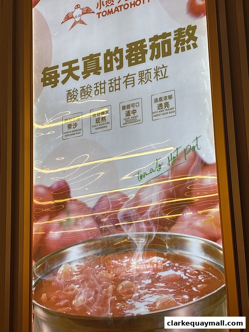 A sign for XiaoYanZi Tomato Hot Pot featuring a steaming bowl of tomato soup and descriptive text.