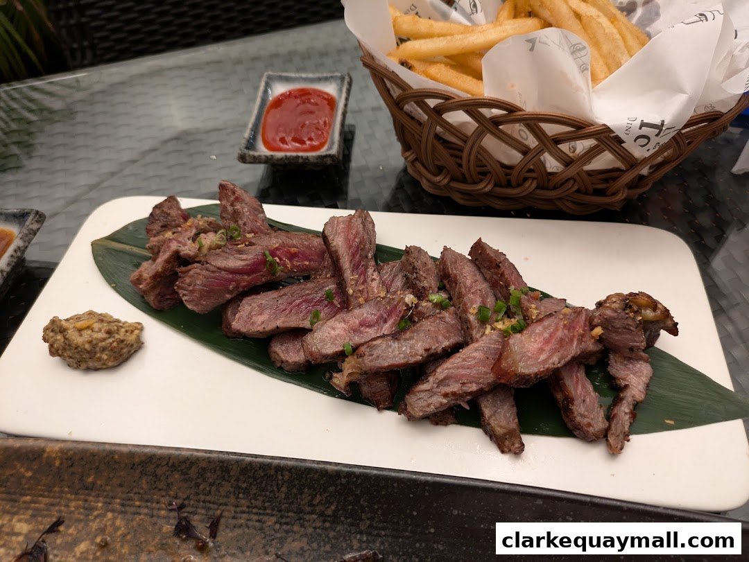 Sliced steak served with fries and dipping sauce on a white plate.