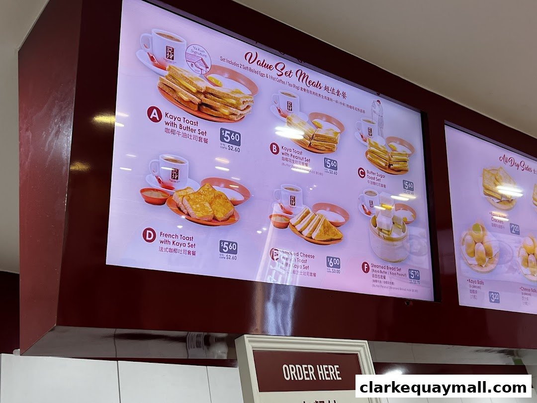 A digital menu board displaying various set meals and side dishes from Ya Kun Kaya Toast.