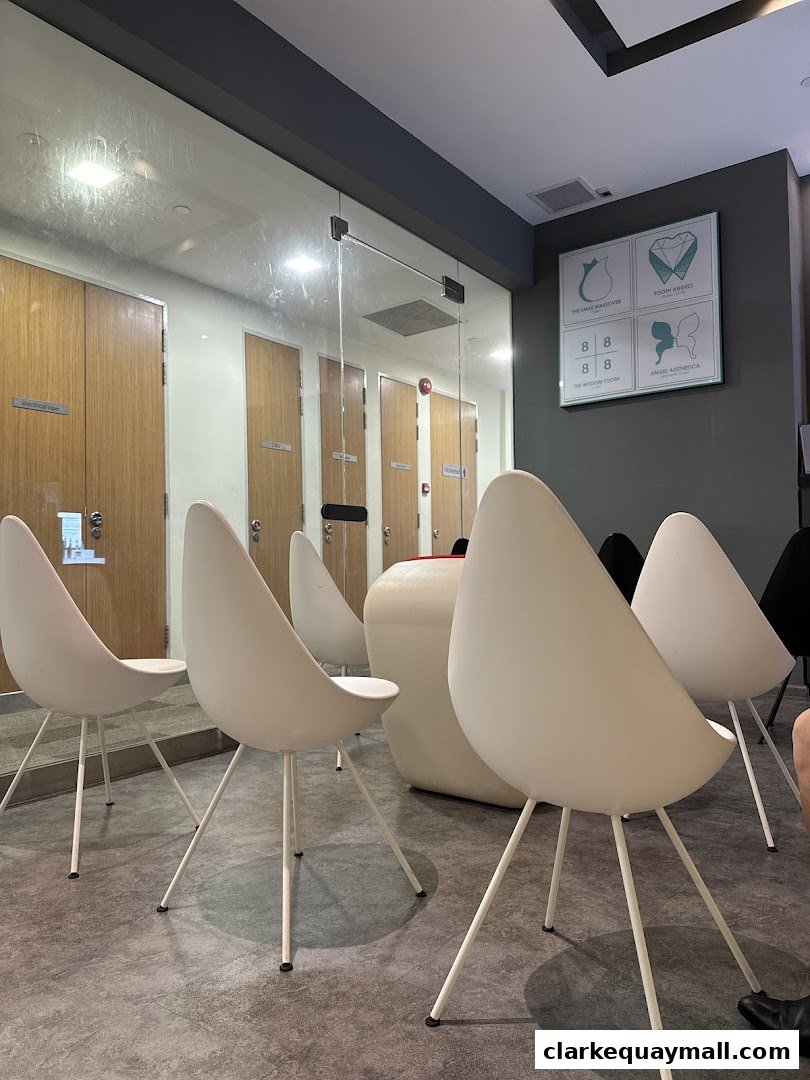 A modern waiting area with white chairs and wooden doors, featuring a dental clinic's promotional display.