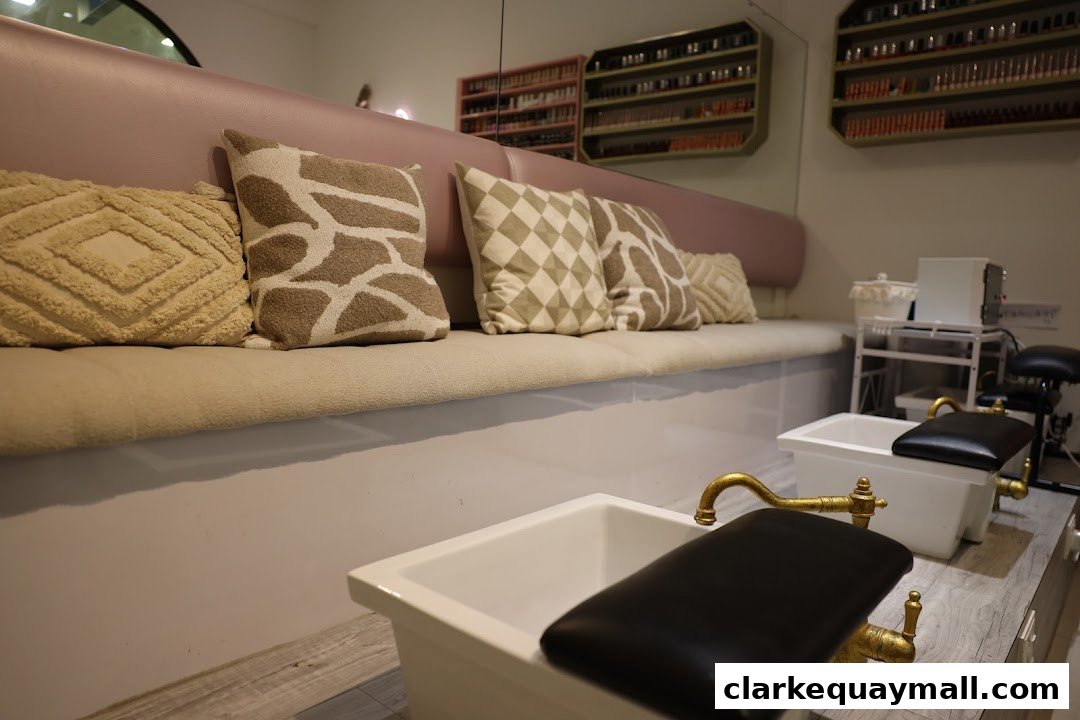 Interior shot of a nail salon with pedicure chairs and a waiting bench with decorative pillows.