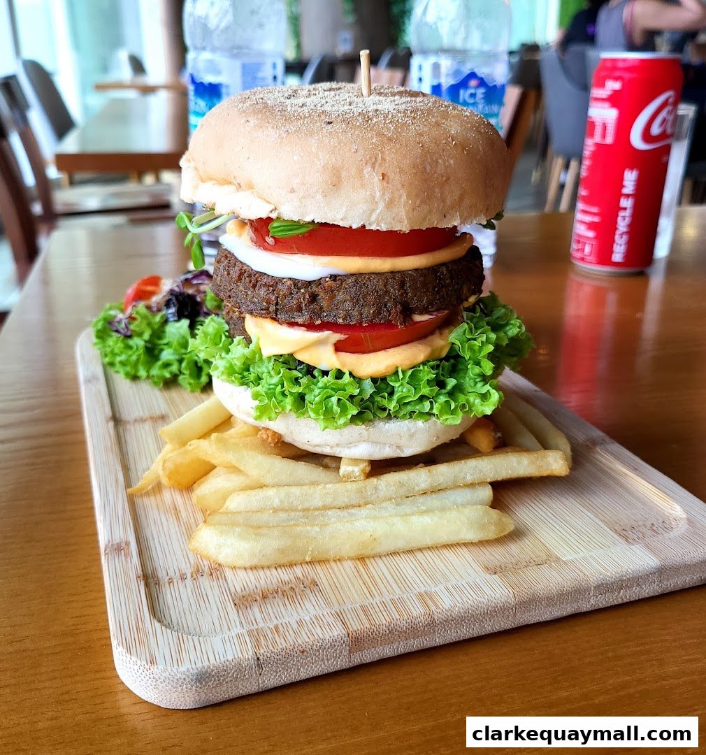 A delicious plant-based burger with fries and a side salad, served on a wooden board.