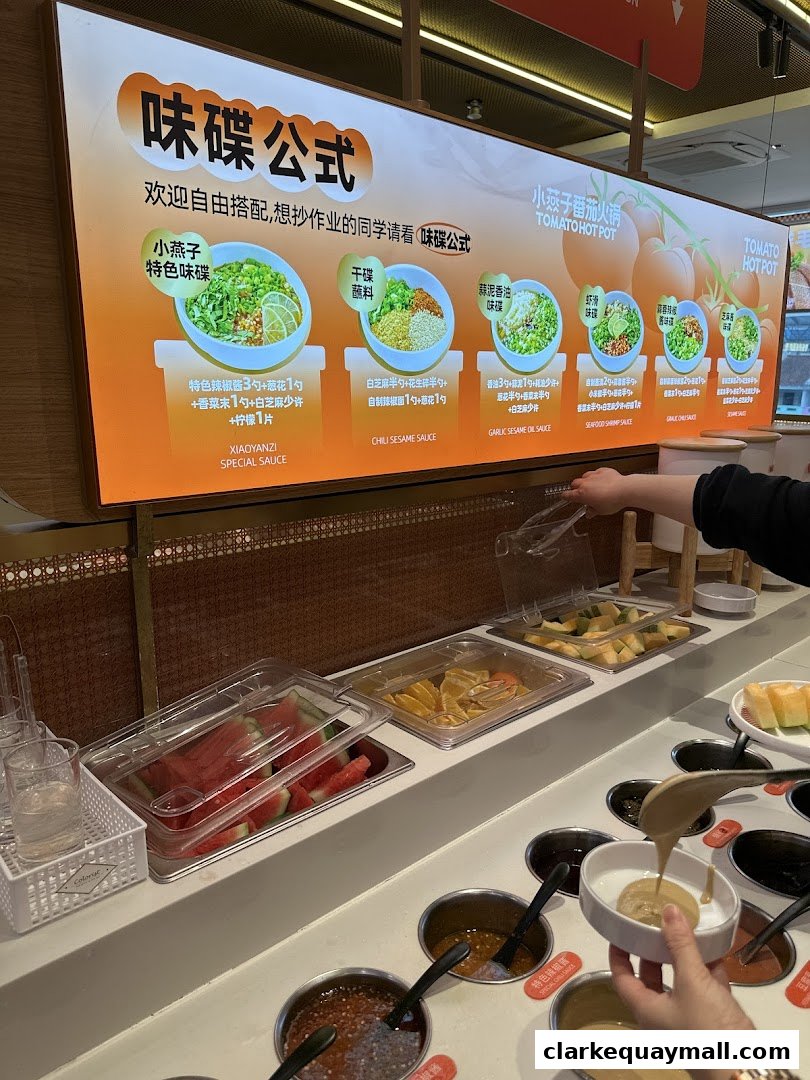 A person is making a sauce at a condiment bar with various ingredients and fruits.