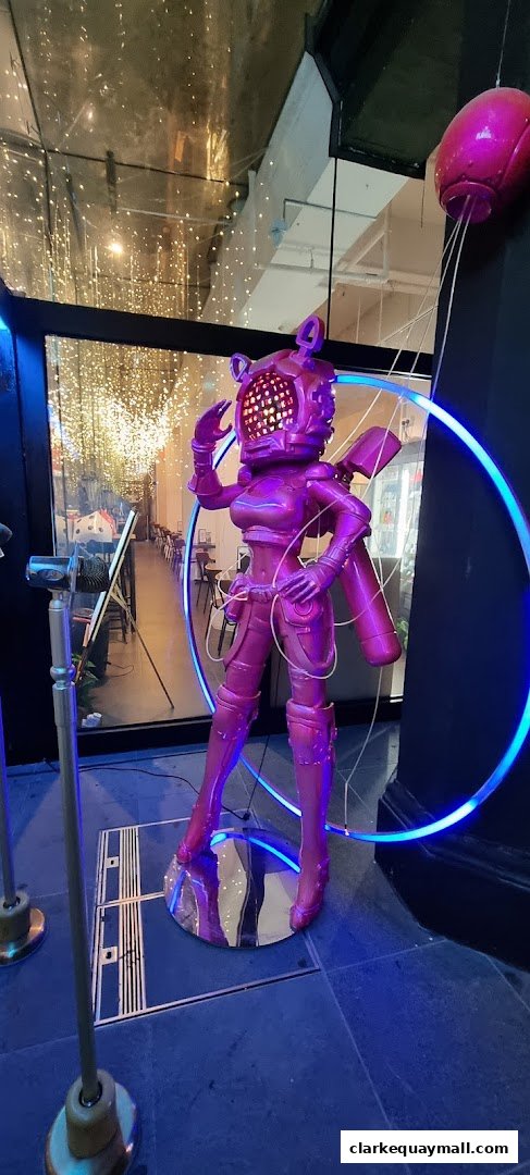 A striking purple robot statue with glowing eyes and neon accents stands in front of a shop.